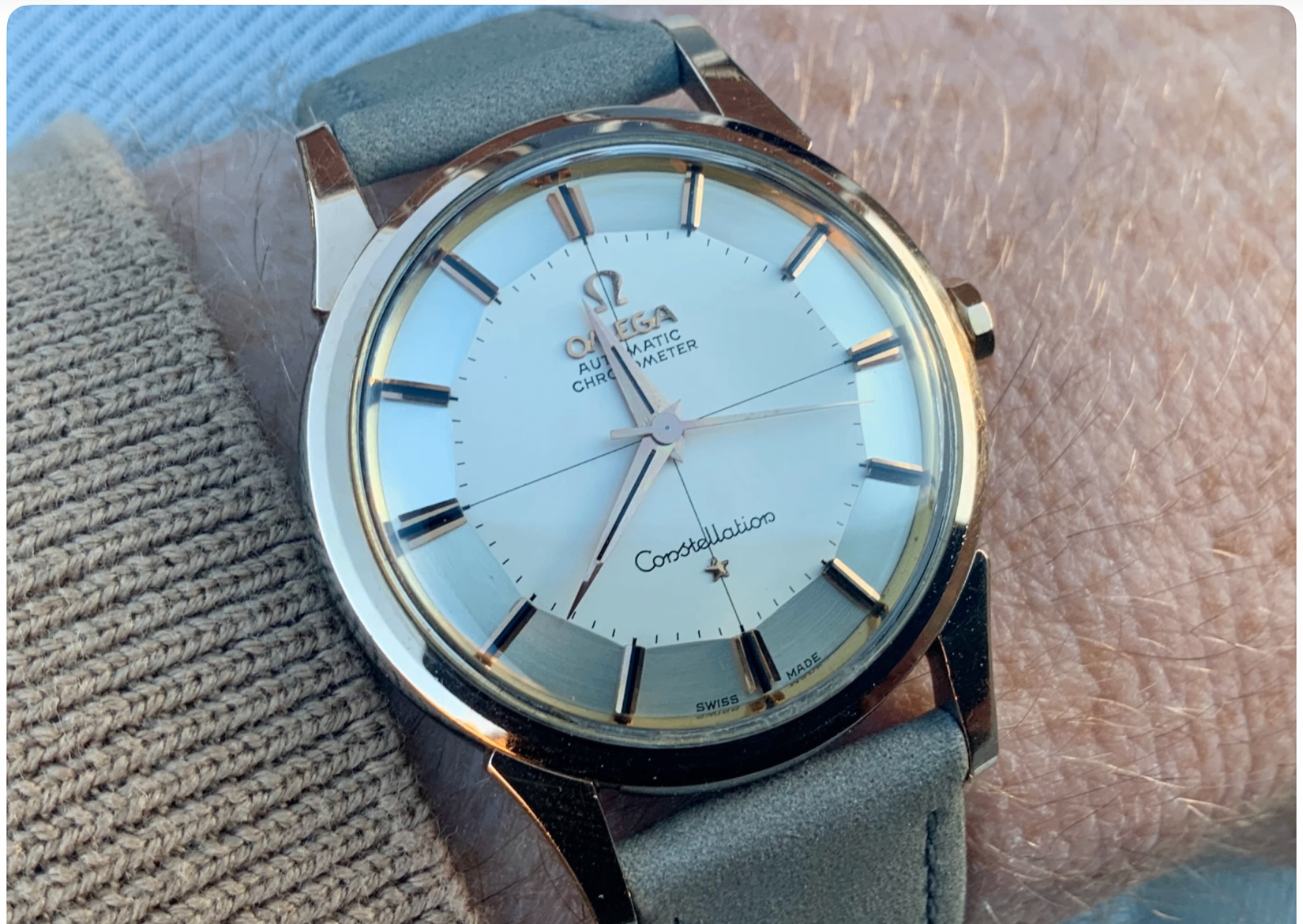Omega Constellation Automatic Chronometer on the wrist, grey suede strap against a knitted sleeve